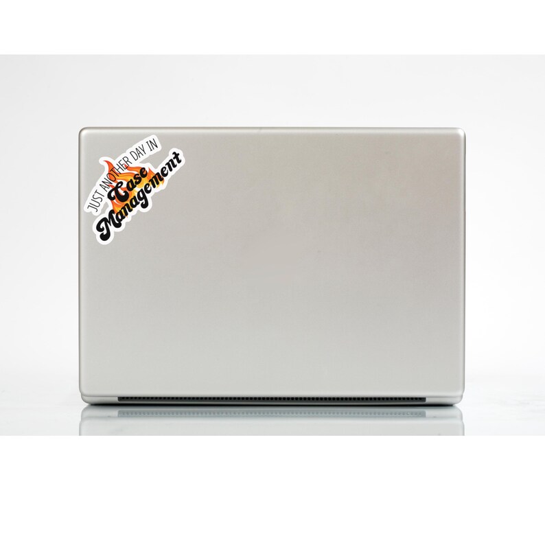 May include: A silver laptop with a sticker that says "Just another day in Case Management". The sticker has a flame design with orange and yellow colors.