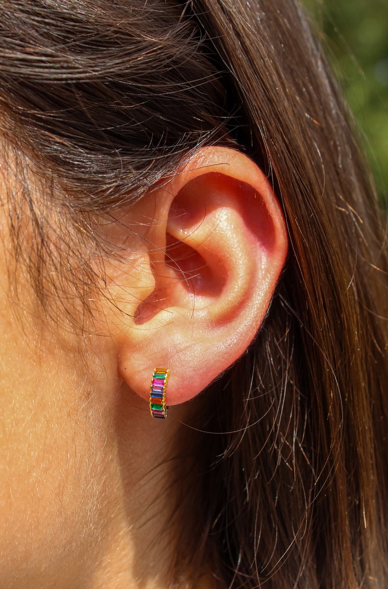 May include: A gold hoop earring with a rainbow of colorful baguette-shaped stones.