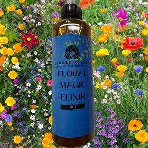 May include: A brown bottle of Floral Magic Elixir with a blue label, set against a backdrop of colorful wildflowers. The label features text and a woman's silhouette. The bottle contains 8 fluid ounces.