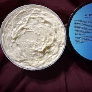 Puede incluir: Un tarro de Edge Growth Butter, 227g, con tapa azul claro y crema blanca. La tapa tiene el texto "12 Tribes On Earth" e instrucciones. La crema tiene una apariencia espesa y texturizada.