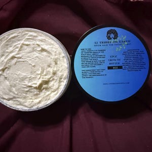 Puede incluir: Un recipiente abierto de Edge Growth Butter con una textura cremosa blanquecina se encuentra junto a su tapa. La tapa es azul con texto blanco y un logotipo. El producto es de 227g.