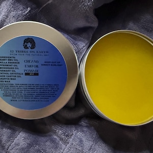 May include: A round metal tin of 8oz Creamy Emu Oil Pomade by 12 Tribes on Earth. The blue label lists ingredients including emu oil, peppermint, lemongrass, rosemary, menthol, castor oil, paraffin wax, and beeswax. The open tin reveals yellow pomade.