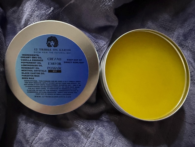 May include: A round metal tin of 8oz Creamy Emu Oil Pomade by 12 Tribes on Earth. The blue label lists ingredients including emu oil, peppermint, lemongrass, rosemary, menthol, castor oil, paraffin wax, and beeswax. The open tin reveals yellow pomade.