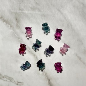 May include: Assortment of ten small, clear glass bear figurines in various shades of pink, purple, blue, and green.