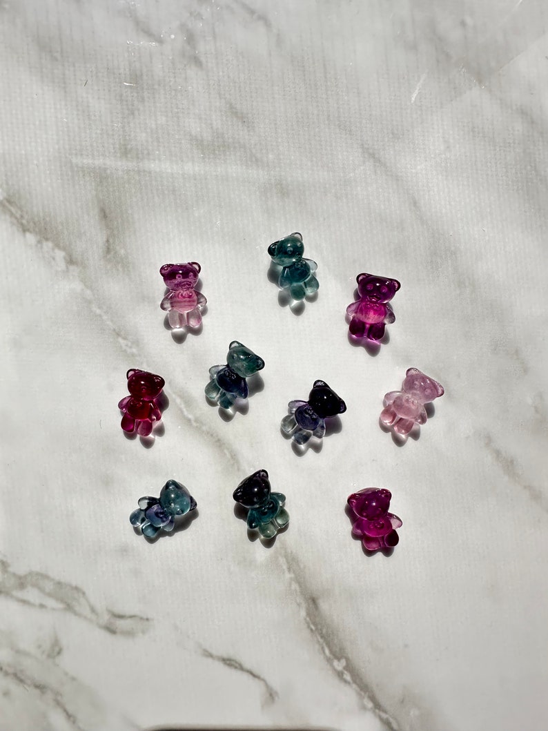 May include: Assortment of ten small, clear glass bear figurines in various shades of pink, purple, blue, and green.