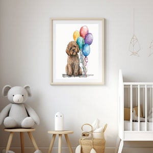 Puede incluir: Una pintura de acuarela de un caniche marrón sentado con un montón de globos de colores. La pintura está enmarcada y colgada en una pared blanca en una guardería.