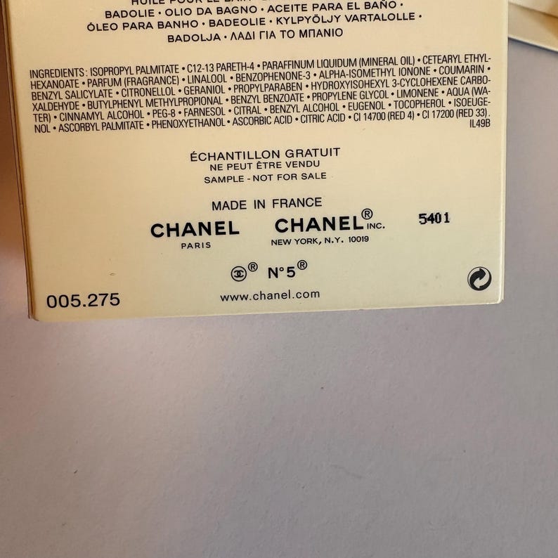May include: A close-up of a cream-colored product box with black text. The box features the Chanel logo, the words "&Eacute;CHANTILLON GRATUIT" and "SAMPLE - NOT FOR SALE". The box also includes a list of ingredients.