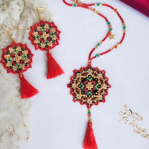 May include: A red beaded necklace and earrings set with a mandala design. The necklace and earrings feature red, green, black, and gold beads. The necklace has a gold star charm and a red tassel. The earrings have red tassels.