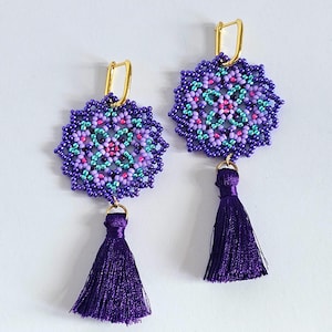 May include: Purple and teal beaded earrings with a gold hook and a purple tassel.