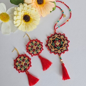 May include: A red beaded necklace with a mandala-shaped pendant and red tassels. Matching earrings with red tassels are also included.