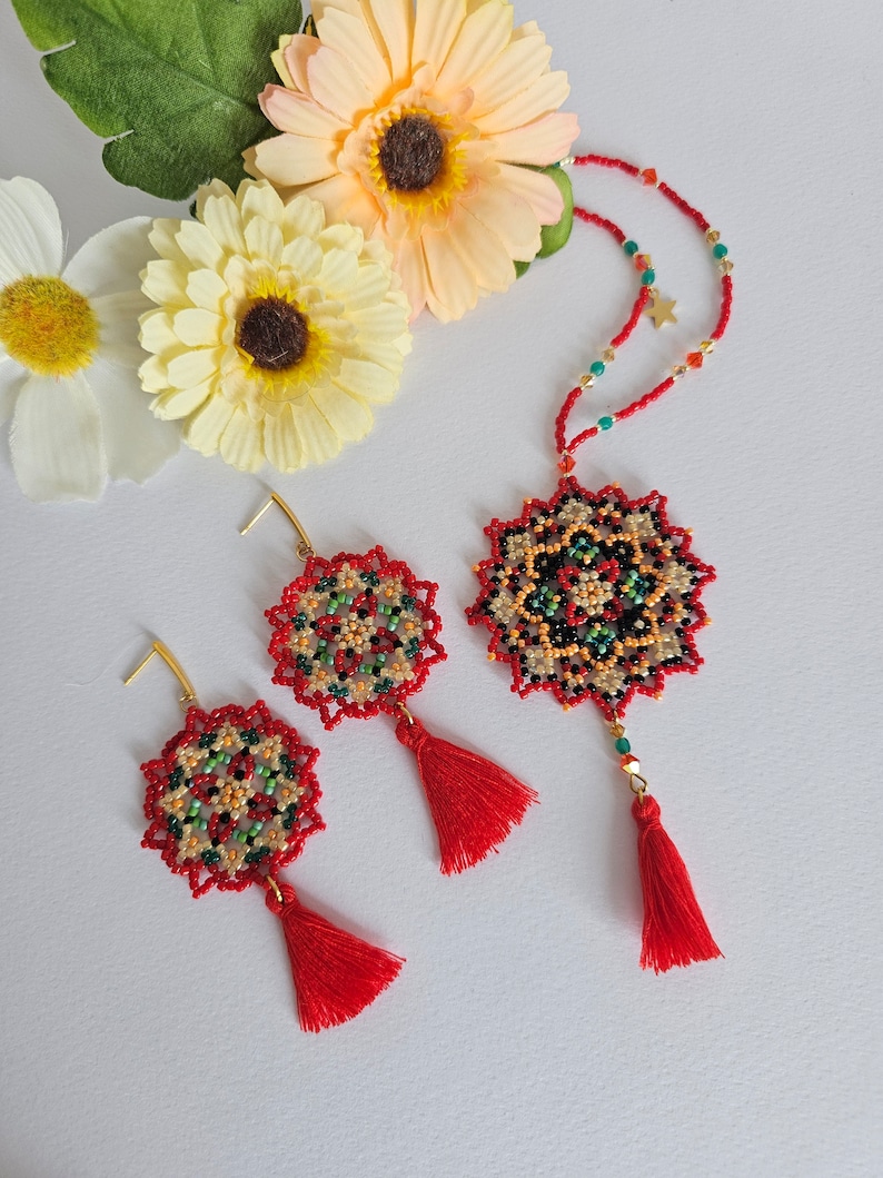 May include: A red beaded necklace with a mandala-shaped pendant and red tassels. Matching earrings with red tassels are also included.