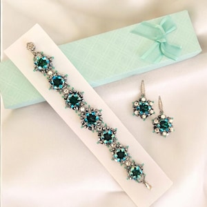 May include: A set of teal and silver beaded jewelry, including a bracelet and earrings. The bracelet has five large teal beads with silver accents, and the earrings are dangling with a similar design.