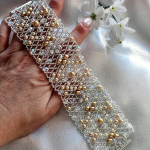 Peut inclure: Un bracelet en argent et or composé de perles. Le bracelet est fait de petites perles rondes de différentes tailles et couleurs, notamment argent, or et transparent.