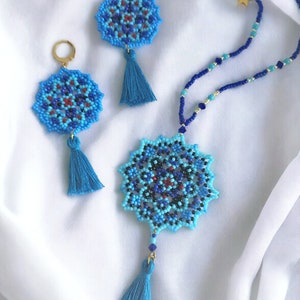 May include: A blue and black beaded necklace with a star charm and a matching pair of earrings. The necklace and earrings feature a mandala design with a blue tassel.