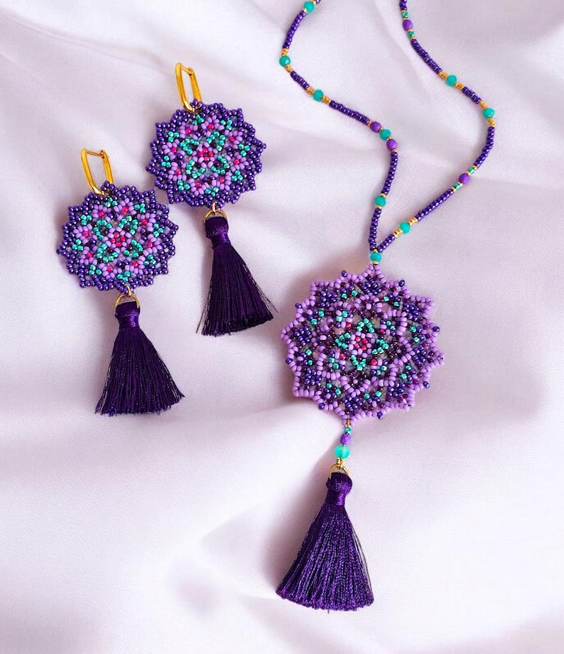May include: A purple and turquoise beaded necklace with a mandala pendant and matching earrings. The necklace and earrings have purple tassels.