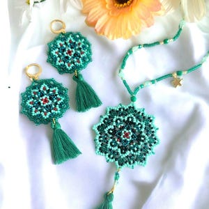 Può includere: Un set di gioielli in perle verdi con un ciondolo a forma di stella, con un design a mandala e dettagli a nappa.