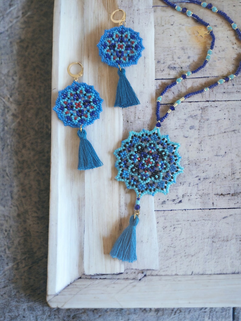 May include: A set of blue and black beaded earrings and a necklace with tassel accents. The jewellery features a mandala design.