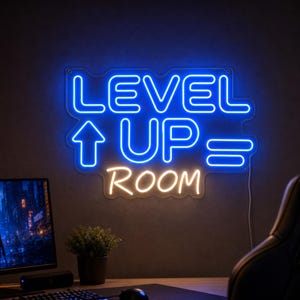 May include: A wall-mounted neon sign featuring the blue text LEVEL UP and an upward-pointing arrow, with the word ROOM in white script below. The sign is mounted on a dark wall above a computer desk setup with a monitor, keyboard, and mouse.
