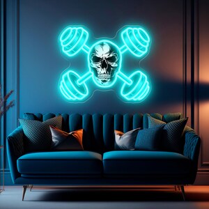 May include: A neon sign featuring a skull and barbells in a cross shape, emitting a bright turquoise glow. The sign is mounted on a dark blue wall above a blue velvet sofa with decorative pillows. The room has a modern aesthetic.