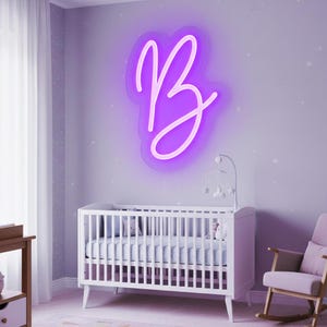 Op de afbeelding: Een kinderkamerscène met een witte wieg, een schommelstoel en een neonbord aan de muur. Het bord toont de letter "B" in een cursief lettertype, verlicht met een heldere paarse gloed. De kamer is geschilderd in zachte lavendeltinten.