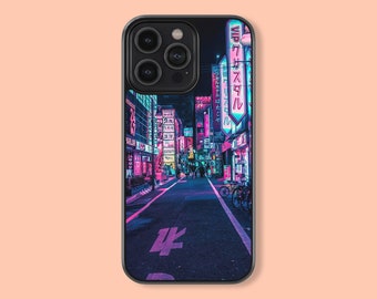 May include: A black phone case with a neon cityscape design. The case features a photo of a street in Japan with bright pink and blue neon signs. The text on the signs is in Japanese.