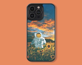 May include: A black phone case with a colorful sunset and an astronaut standing in a field of sunflowers.