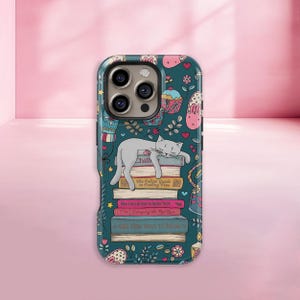 Op de afbeelding: Een teal telefoonhoesje met een ontwerp van een slapende grijze kat op een stapel boeken. De boeken hebben titels als "The Feline Guide to Feeling Fine" en "1001 New Ways to Relax". De hoes is versierd met cupcakes, harten en bloemmotieven.