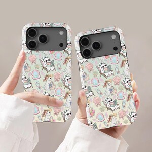 Puede incluir: Dos fundas para teléfono con un patrón repetitivo sobre un fondo amarillo claro. El diseño incluye fantasmas blancos con gafas de sol, leyendo libros y llevando bolsos, intercalados con conchas rosas, perlas en conchas y chanclas azul claro.