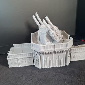 May include: A light gray, 3D-printed model of a turret with multiple cannons. The model has a detailed design with architectural elements and is likely for tabletop gaming or model building.