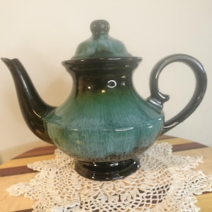 Könnte beinhalten: Eine grüne und schwarze Teekanne aus Keramik mit Deckel. Die Teekanne hat eine glasierte Oberfläche mit einem gestreiften Muster.