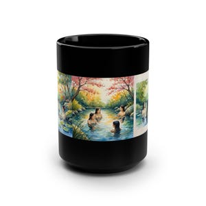 May include: Black ceramic coffee mug with a wraparound watercolor illustration of women bathing in a natural hot spring. The scene includes trees, water, and a colorful landscape. The mug is a standard 15 oz size.