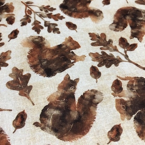 May include: A white fabric with a repeating pattern of brown squirrels and oak leaves. The squirrels are painted in a watercolor style and have a brown and tan color.