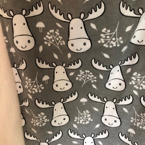 May include: A gray fabric with a white moose and berry pattern. The moose have smiling faces and large antlers.
