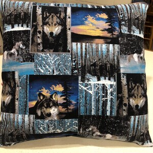 May include: A black and blue throw pillow with a repeating pattern of wolves in a snowy forest. The pillow features a sunset scene with a lake and trees.