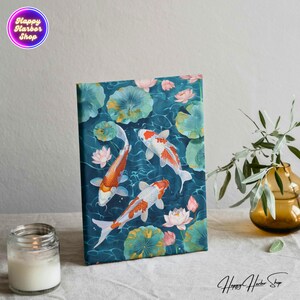 May include: A canvas print featuring three orange and white koi fish swimming in a blue pond with green lily pads and pink lotus flowers.