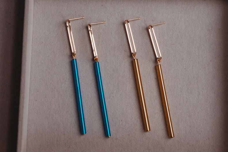 Peut inclure: Quatre longues boucles d'oreilles fines avec des crochets dor&eacute;s et des tiges pendantes. Deux tiges sont dor&eacute;es et deux sont bleues.