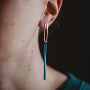 Peut inclure: Une paire de longues boucles d'oreilles bleues et dor&eacute;es. Les boucles d'oreilles sont compos&eacute;es d'une tige bleue fine avec une boucle dor&eacute;e en haut.