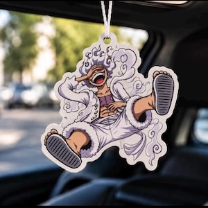 Könnte beinhalten: Ein hängender Auto-Lufterfrischer mit einer Zeichentrickfigur mit wildem weißem Haar, einem breiten lachenden Gesichtsausdruck und einem weißen Outfit. Die Figur ist in einer dynamischen Pose dargestellt, umgeben von wirbelnden weißen Wolken.