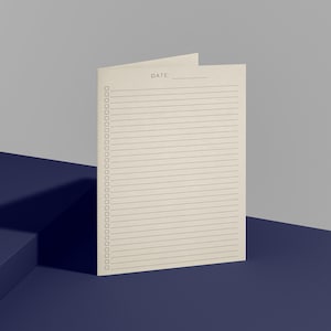 May include: A blank, lined notepad with a section at the top for the date. The notepad is beige and has a slightly textured surface. It is standing on a blue surface.