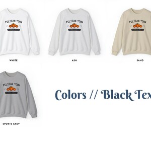 May include: Four sweatshirts in different colors: white, ash, sand, and sports grey. Each sweatshirt features a graphic design with the text "PELICAN TOUN" and a small image of three pumpkins. The text is black.