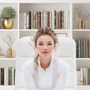 May include: A woman in a white shirt sits in front of a white bookshelf filled with books, decorative vases, and potted plants. The bookshelf is divided into sections, creating a visually organized display. The woman is the focal point, with a soft, neutral background.