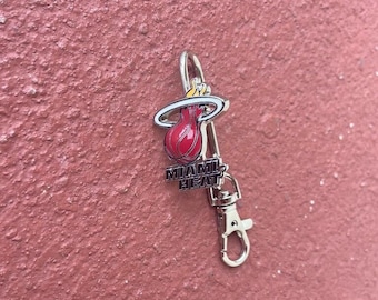 May include: Silver keychain with a red, orange, and yellow Miami Heat basketball logo and the words "Miami Heat".