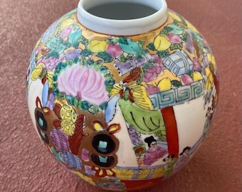 May include: A round, white porcelain vase with a gold rim and intricate floral and geometric designs in shades of pink, green, blue, red, and gold. The vase is decorated with figures of people and butterflies.