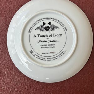 May include: White porcelain plate with a black and white cat illustration and the text "A Touch of Ivory" by Daphne Baxter. The plate is a limited edition fine porcelain piece, plate number JA4602.