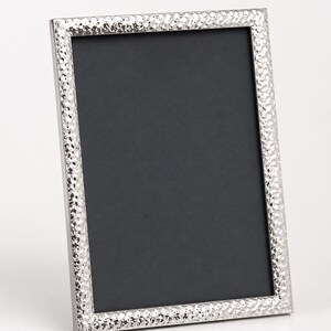 May include: A rectangular picture frame with a metallic silver finish and a hammered, dimpled texture along the border. The frame features a clean, sharp edge design and contains a solid black rectangular insert within the central display area.