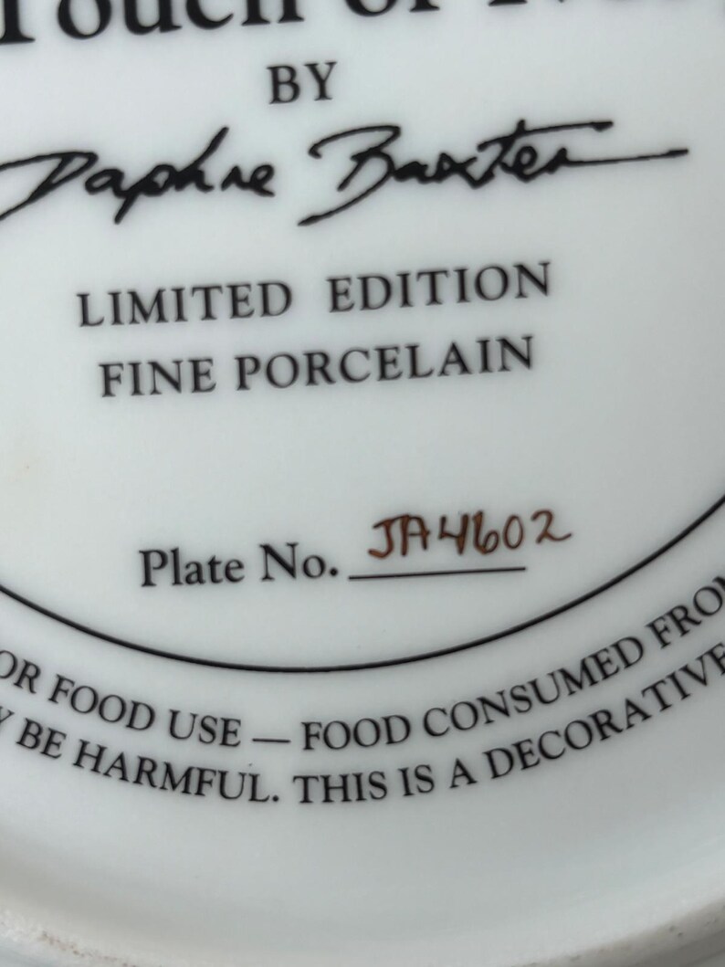 May include: White porcelain plate with black text that reads "LIMITED EDITION FINE PORCELAIN" and "Plate No. JA4602". The plate is signed "Daphne Baxter". The plate is for decorative use only.