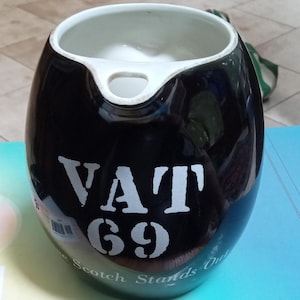 Può includere: Brocca in ceramica nera con interno bianco e beccuccio. Le parole "VAT 69" sono stampate in bianco, con "The Scotch Stands Out" stampato sotto. La brocca ha una finitura lucida.