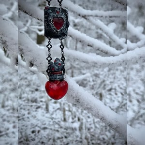 Naszyjnik z eliksirem miłosnym — czerwona szklana fiolka i księga czarownic, wisiorek w stylu gotyckiej fantazji, biżuteria z zimowego lasu, prezent z mrocznej bajki