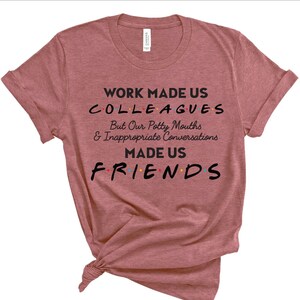 May include: A heather pink t-shirt with the text "WORK MADE US COLLEAGUES But Our Potty Mouths & Inappropriate Conversations MADE US FRIENDS" in black text with colorful dots.
