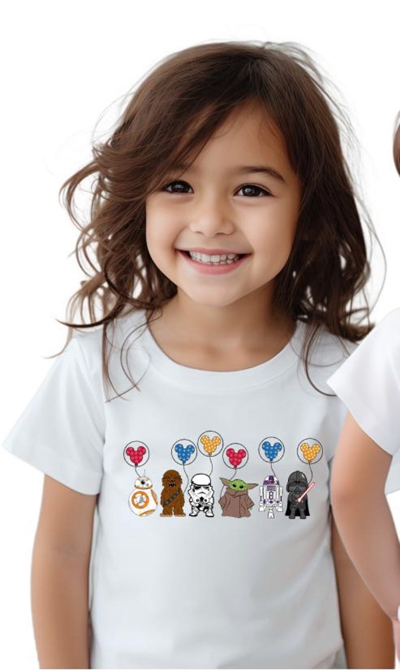 May include: White t-shirt featuring cartoon characters from Star Wars, including BB-8, Chewbacca, a Stormtrooper, Yoda, R2-D2, and Darth Vader. Each character is holding a balloon with a Mickey Mouse head design. The shirt is worn by a child.